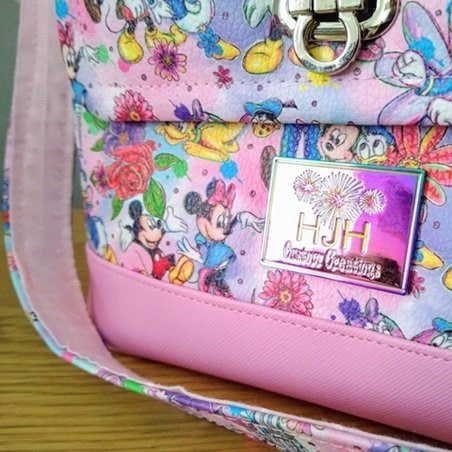 Pink patterned bag with a rectangular iridescent metal logo plate